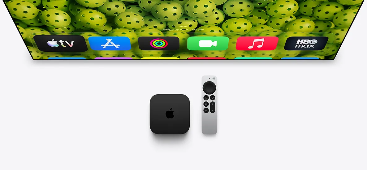 Apple TV 4K and Siri Remote below TV screen, screen shows Home Screen top row app icons over a green pickleballs background