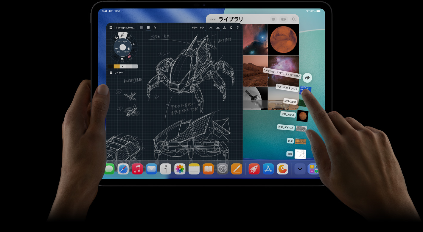 iPad Proの前面の外観、横向き、ダウンロードフォルダから扇状に広がったファイルを指差している右手。ディスプレイにはiPadOS 26のインターフェイスが表示されており、ロボットの詳細な設計図、手書きの注釈、複数のデザイン工程を表示した写真編集アプリ、写真ライブラリなど、複数のアプリが開かれている