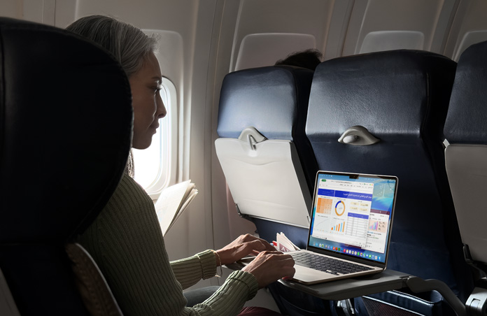 شخص يعمل على جهاز MacBook Air أثناء جلوسه في مقعد طائرة