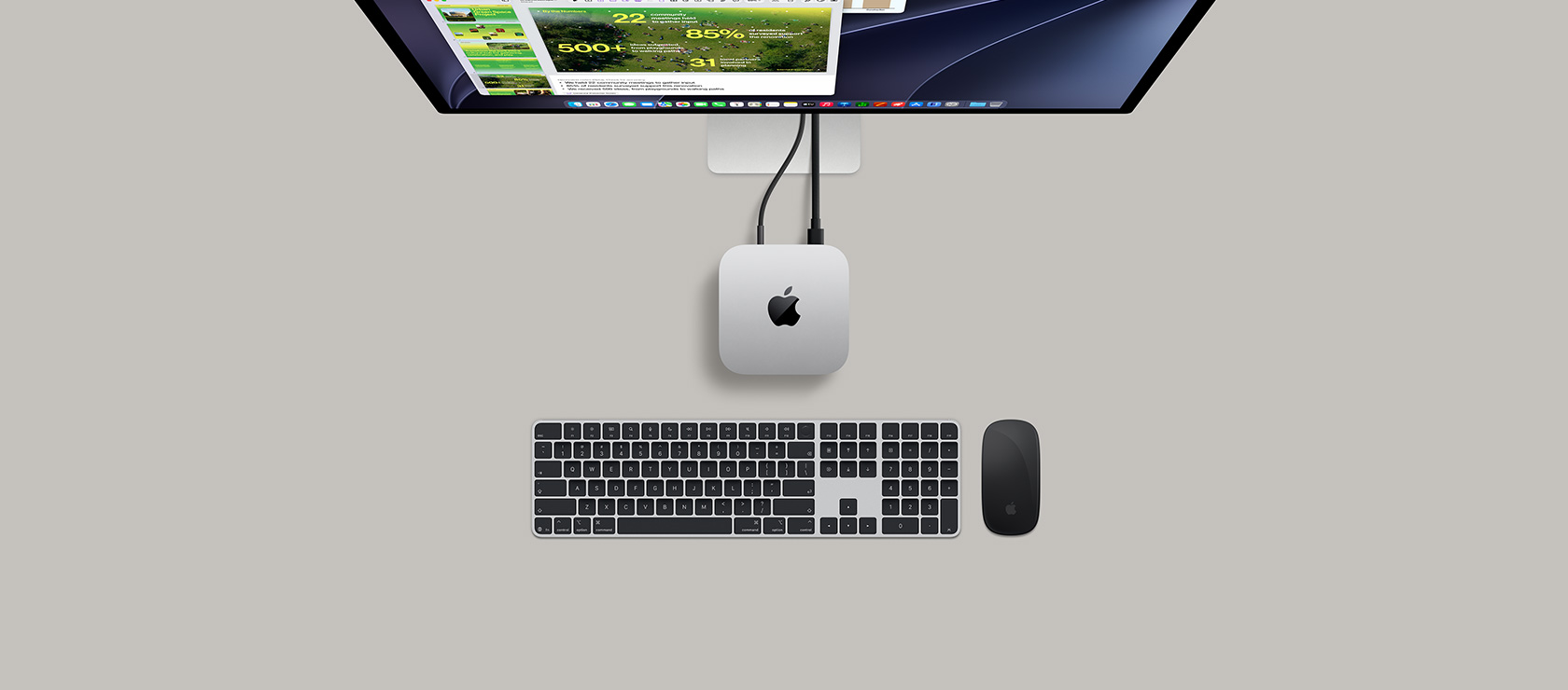 Mac&nbsp;mini, top, silver aluminium, rounded corners, glossy black Apple logo centred, connected by cord, Studio&nbsp;Display partially visible on top with screen showing Calendar app, Keynote presentation, and bar graph open, Magic Keyboard with Numeric Keypad, Magic Mouse visible below Mac mini