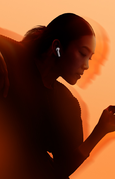 Seseorang mengenakan AirPods 5, lengan tertekuk, latar belakang warna-warni