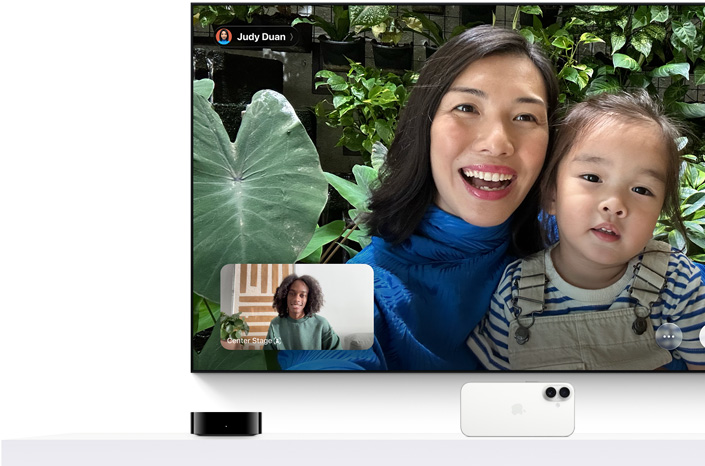 Apple TV 4K 與 iPhone：電視螢幕顯示 FaceTime 通話，畫面中一個人抱著年幼的孩子，另有一位通話人在畫面中另一格位置