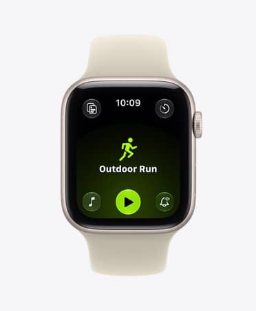 Apple Watch SE 3 z aluminiową kopertą w kolorze księżycowej poświaty i paskiem sportowym w kolorze piasku (jasnobeżowym) wyświetla ekran aplikacji Trening (bieg w plenerze). Na prawym boku urządzenia pokrętło Digital Crown